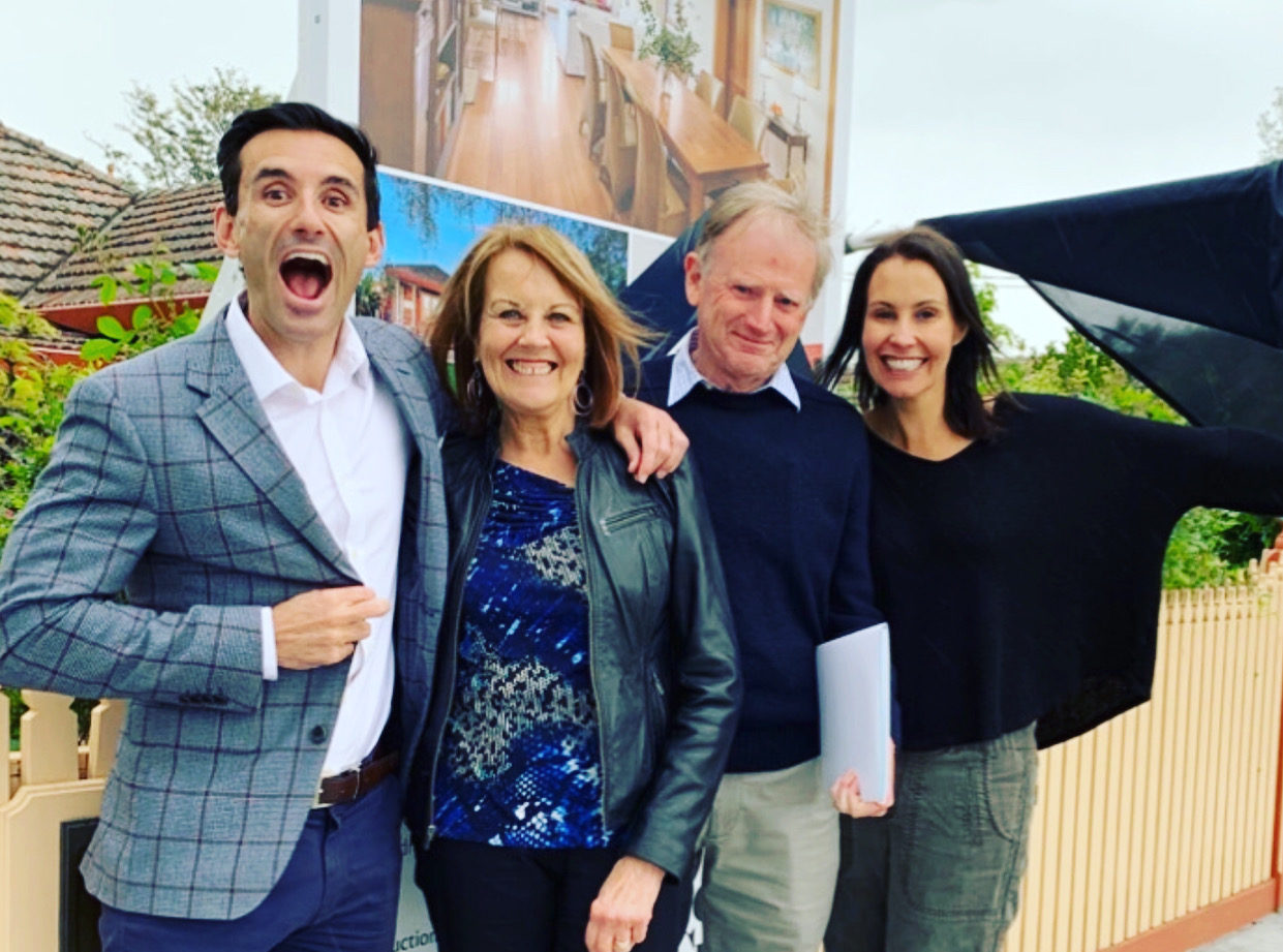 Buyer's agent and three happy people standing in front of sold sign